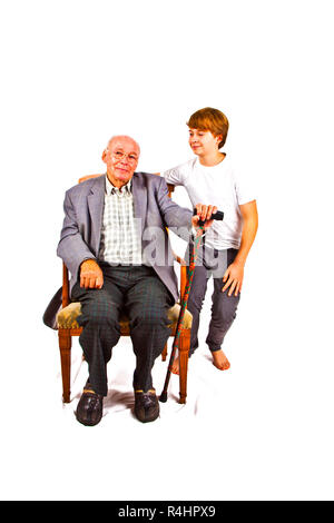 old man sitting in the armchair with his grandchild standing beside him Stock Photo