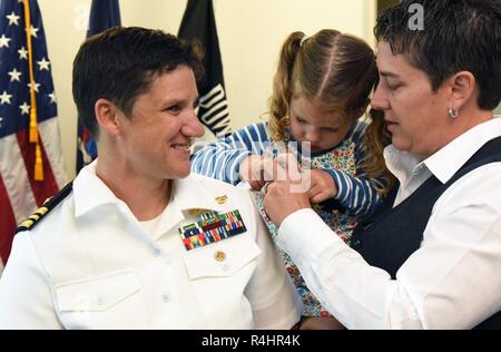GARDEN CITY, New York (Oct. 1, 2018) The wife and daughter of Cmdr. Penny Glover, a native of Uniontown, Pennsylvania and graduate of Northeast Senior High School in Pasadena, Maryland, changing out her shoulder boards to commander during a promotion ceremony at Navy Recruiting District New York headquarters. Glover is the prospective executive officer of the recruiting district and a graduate of Cedar Crest College, the Naval War College and Capella University. Stock Photo