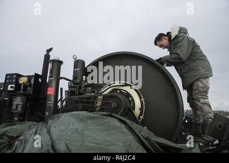 U.S. Air Force Senior Airman Anson Stuart, 52nd Civil Engineer Squadron electrical power production journeyman, inspects a  mobile aircraft arresting system on the flight line at Kallax Air Base, Sweden, Oct. 26, 2018, during Exercise Trident Juncture 18. The Mobile Aircraft Arresting System was brought in from Ramstein Air Base and installed for the F-16 Fighting Falcons during Trident Juncture 2018. Stock Photo