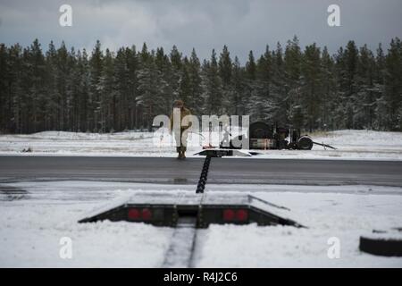 U.S. Air Force Master Sgt. Michael Roderick, left, 52nd Civil Engineer Squadron Noncommissioned Officer-in-charge of electrical power production, inspects a  Mobile Aircraft Arresting System(MAAS) on the flight line at Kallax Air Base, Sweden, Oct. 26, 2018 during Exercise Trident Juncture 18. The MAAS was brought in from Ramstein Air Base and installed for the F-16 Fighting Falcons during Trident Juncture 2018. Stock Photo