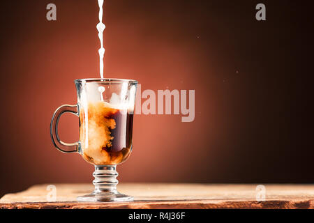 Adding milk to a cup of coffee. Stock Photo