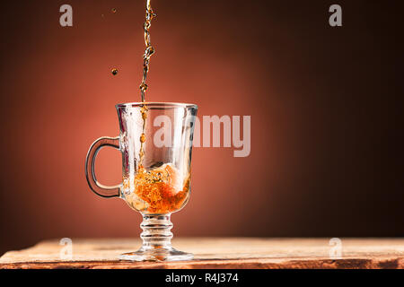 Brown splashes out drink from cup of tea on a brown background Stock Photo