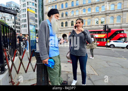 Young Asian woman on her mobile phone in Trafalgar Square, with an older man (father?) London, England, UK. Stock Photo