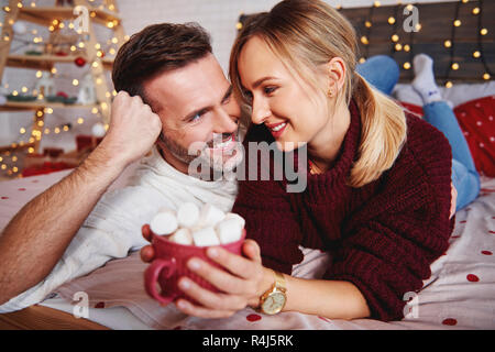 Smiling man embracing his girlfriend in Christmas Stock Photo