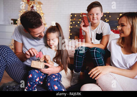 Happy family opening christmas presents in bed