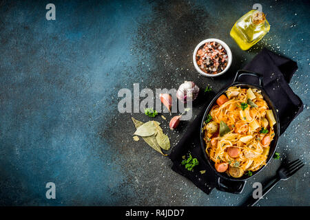 German, polish, Austrian cuisine dish, Bigos - sauerkraut cabbage stewed with meat, mushrooms and sausages, in small pan on dark concrete background.T Stock Photo