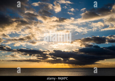 landscape of quiet ocean during a coloured beautiful sunset with lot of dramatic and nice clouds on the sky. Horizon line on the sea and sunrays every Stock Photo