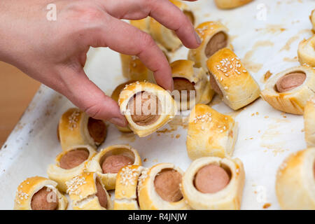 Sausages rolled in croissant dough baked cooling on metal rack. Stock Photo