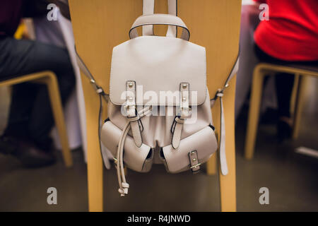 Beige bag hanging on a black chair on grey background. Stock Photo