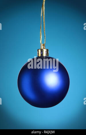 Christmas decoration with blue Ball on blue background with snowflakes falling from sky. Happy holidays composition Stock Photo