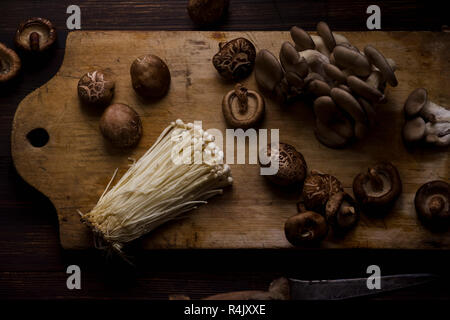 Enoki, shiitake and oyster mushrooms on cutting board Stock Photo