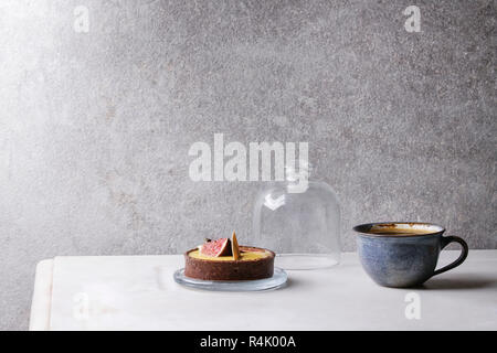 Sweet figs tartlet with cup of coffee espresso standing on white marble table with grey wall at background. Minimalist style. Copy space Stock Photo