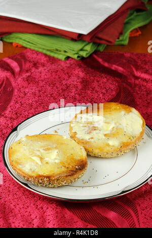 Buttered Everything Bagel on a Plate over a Placemat Stock Photo