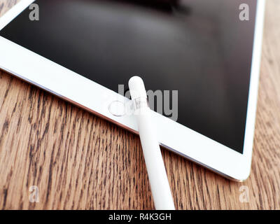 Apple pencil and its cap over a iPad of color white over a wooden surface Stock Photo