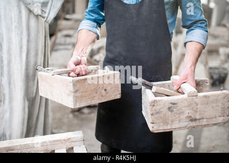 Sculptor with working tools in the studio. Close-up view with no face Stock Photo
