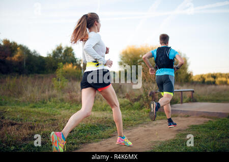Photo on back of sportive woman and man running through park