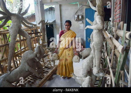 An Indian artist seen carrying clay idol faces of Durga goddesses, ahead of the Durga Puja festival at the studio in Agartala. Durga Puja, the annual Hindu festival that involves the worship of the Durga goddess, who symbolizes power and the triumph of good over evil in the Hindu mythology, culminates in the immersion of the idols bodies in water. Stock Photo