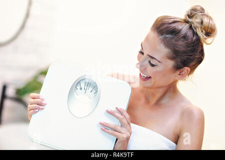 Happy woman holding bathroom scales in bathroom Stock Photo