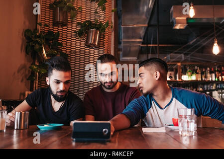 Group of arabian friends taking selfie in lounge bar. Mixed race young men having fun in loft cafe. Hipsters hangout together Stock Photo