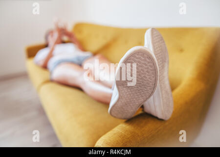 Young woman relaxing sleeping on sofa at home. Focus on foot. Rest concept Stock Photo