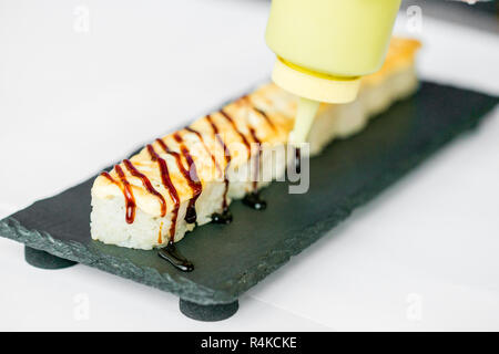 Putting sauce on uncut Japanese sushi roll Stock Photo