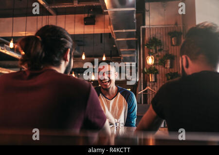 Group of mixed race young men talking in lounge bar. Multiracial friends having fun in cafe drinking coffee Stock Photo