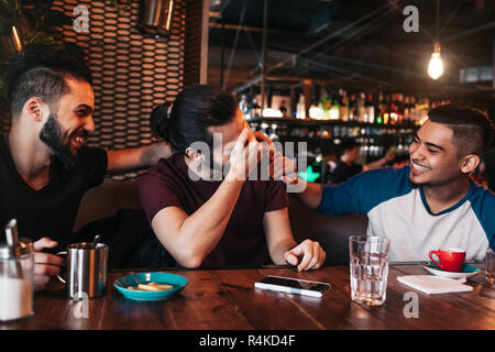 Happy arabic young men hanging in loft cafe. Group of mixed race people having fun in lounge bar. Friends chilling out and laughing Stock Photo