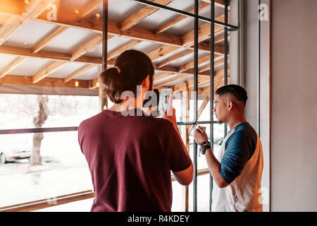 Young man takes a picture of his arabian friend on smartphone. Best friends spending time in cafe drinking tea. Stock Photo