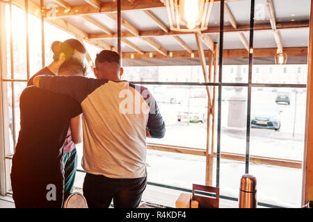 Group of friends hugging and checking pictures on smartphone in lounge bar. Young men having fun spending time together Stock Photo