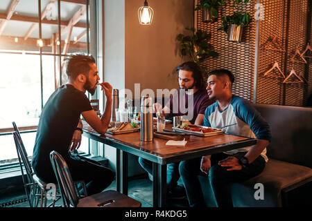 Group of mixed race young men talking in lounge bar. Multiracial friends having fun in cafe drinking coffee Stock Photo