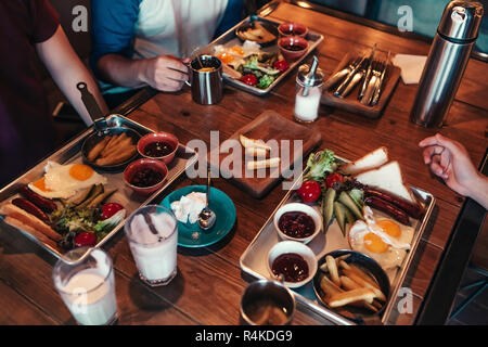 Breakfast in cafe. Friends eat breakfast in cafe. Young men having tasty food and drinks in bar. Stock Photo