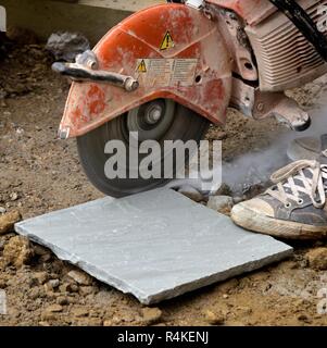 Stone paving slab being cut with a circular petrol powered saw Stock Photo