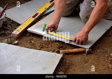 A builder measuring stone paving slabs Stock Photo