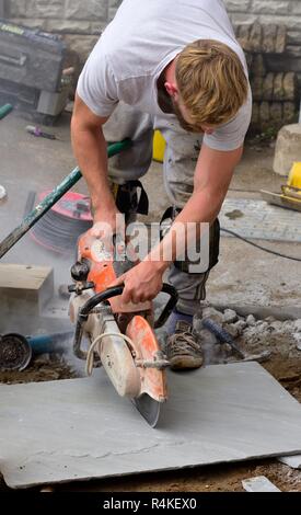 Stone paving slab being cut with a circular petrol powered saw Stock Photo