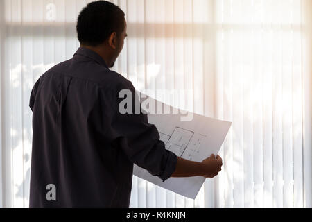 Architect working in a office. Engineer holding blueprint in office, architectural concept Stock Photo