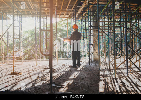Engineer with blueprint in building construction site Stock Photo