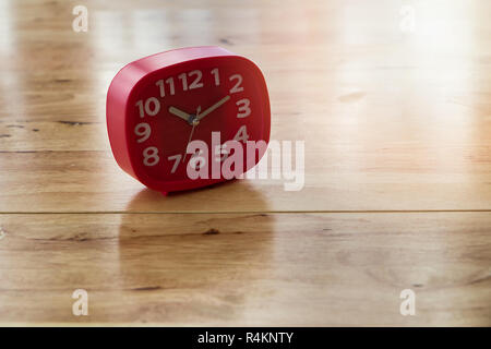 Red alarm clock on wooden desk Stock Photo