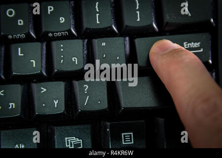 Man typing on a keyboard with letters in Hebrew and English Stock Photo