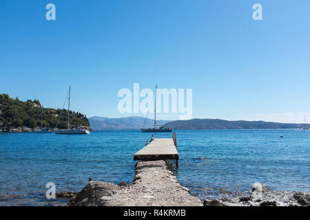 Long wooden pontoon leading into the sea at the pretty coastal village of Kalami in Corfu Stock Photo