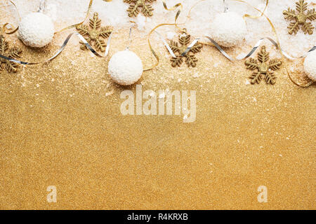 Beautiful christmas silver and white deco baubles with golden snowflake deco over powdery snow on golden glitter background. Flat lay design. Copy Spa Stock Photo