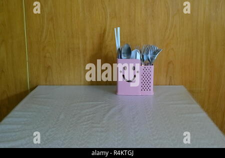 closeup of cute cutlery box with smiling face on dining table covered with tablecloth, positive thinking concept Stock Photo