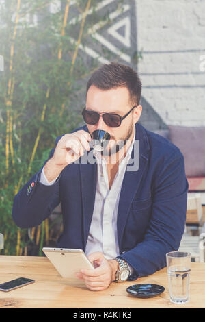Handsome fashionable guy drinking coffee and holding digital tablet device. Stock Photo