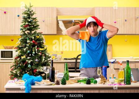 Young man cleaning kitchen after Christmas party Stock Photo