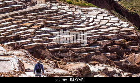 Salt mines and basins with peruvian worker in front, Salineras de Maras. Peru Stock Photo