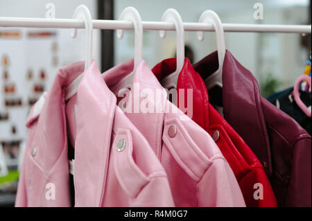 Leather womans jackets is on sale in shop at hanger pink and red colors Stock Photo