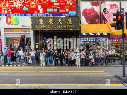 People waiting at the crosswalk outside Chungking Mansions, Nathan Road, Tsim Sha Tsui, Kowloon, Hong Kong Stock Photo
