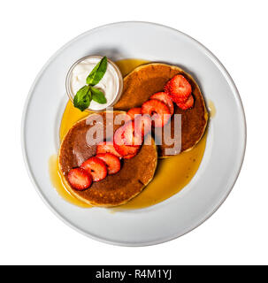 Thick, spongy American pancakes with warm maple syrup, strawberries and cream. Stock Photo