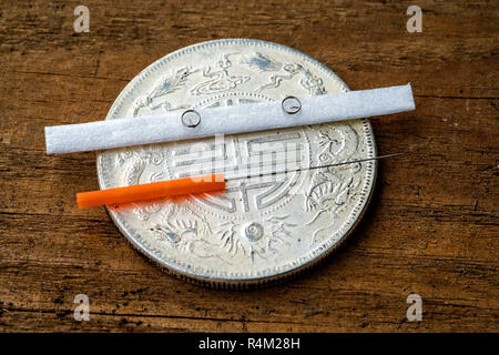 acupuncture needle on antique chinese coin Stock Photo