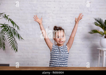 Excited little girl with arms outstretched up with a victorious smile ...