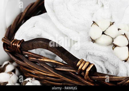 Laundry basket filled white fluffy towels, cotton flowers and a bottle of  liquid soap against a blurred grey background Stock Photo - Alamy